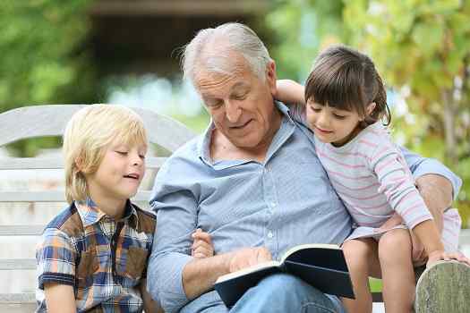 Grandfather reading book with two children.